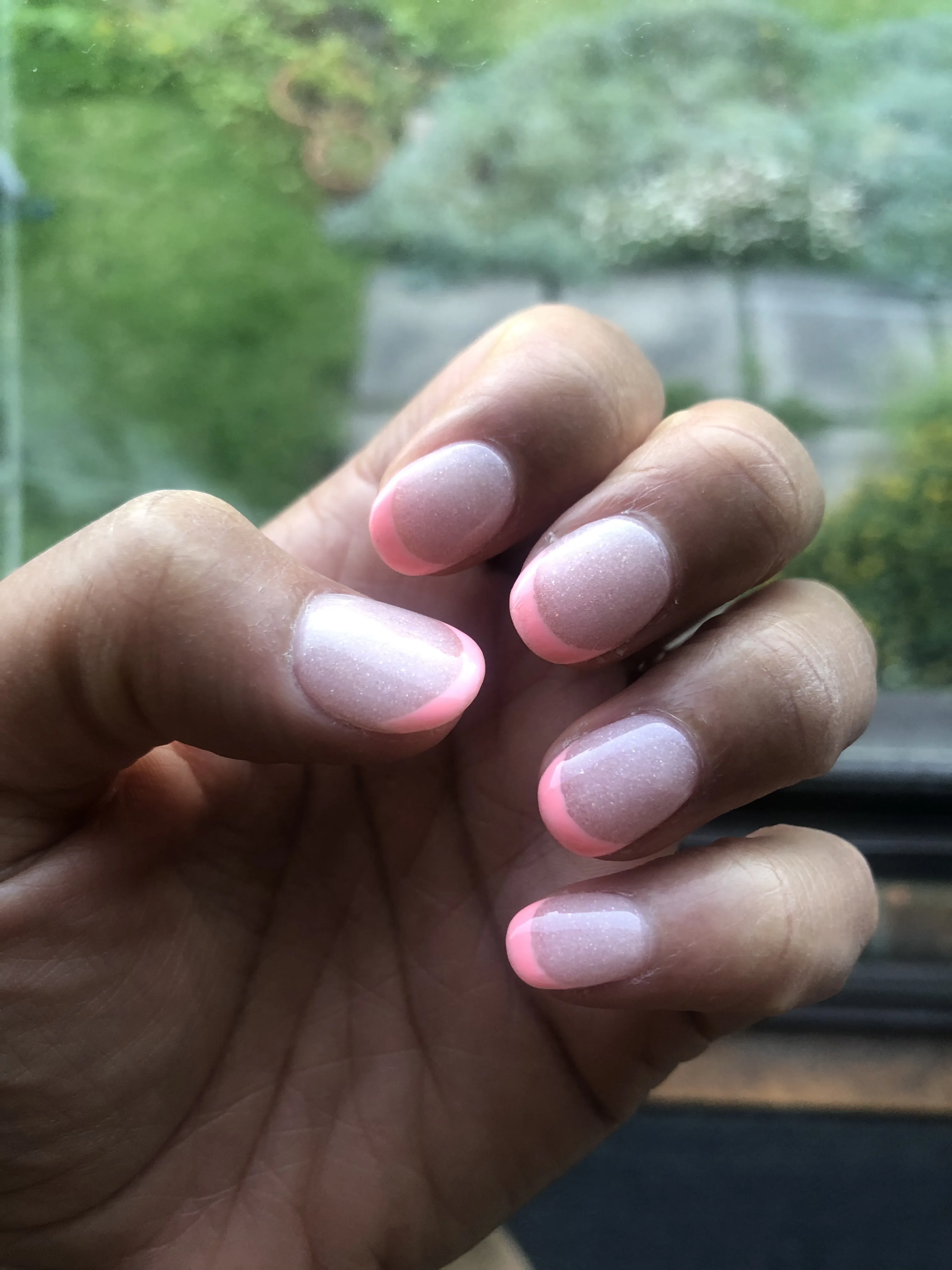 Pink and white French-ombre glitter round nails with a garden window behind